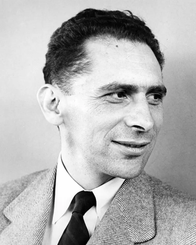 Person in a suit looking to the side, with short, dark hair, in a black-and-white photo.
