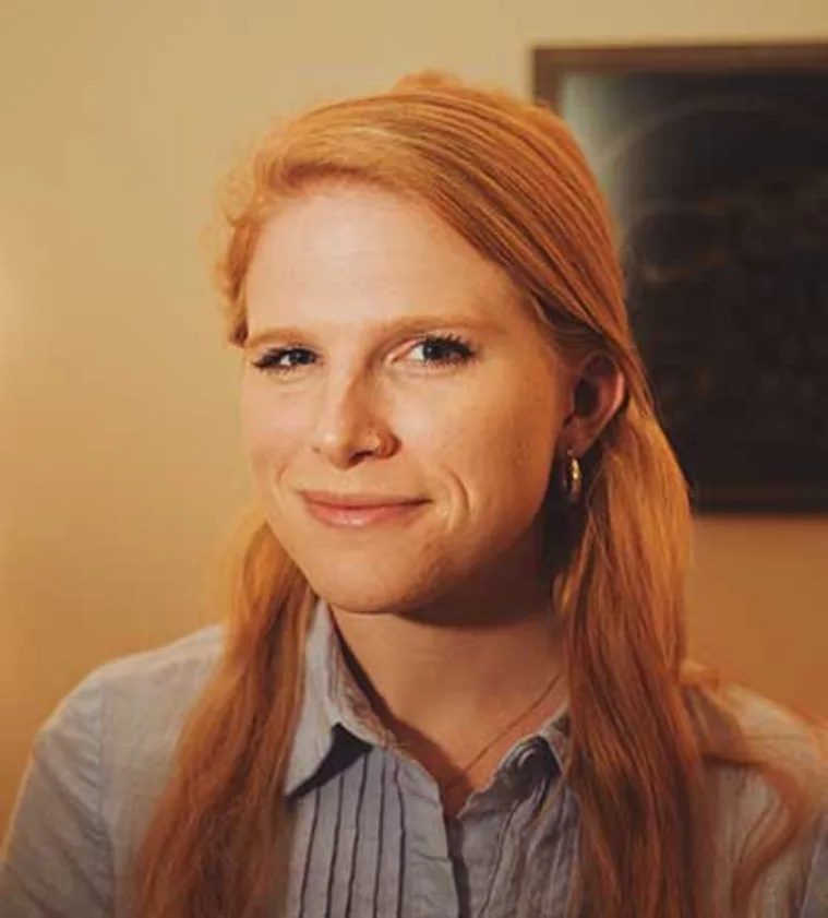 Person with long red hair, smiling slightly, wearing a light shirt.