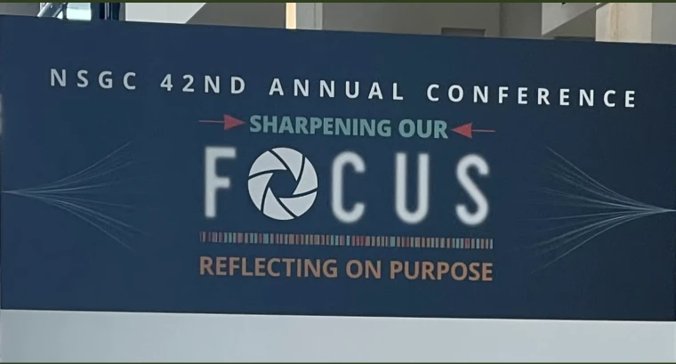 NSGC 42nd Annual Conference sign with "Sharpening Our Focus" and "Reflecting on Purpose" text, featuring a camera aperture icon.