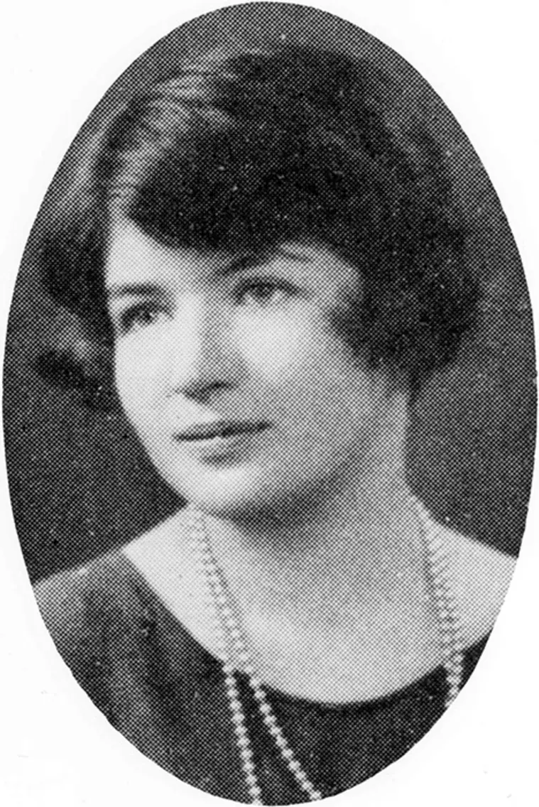 Person with short dark hair wearing a beaded necklace, dressed in formal attire, in a vintage black and white oval portrait.