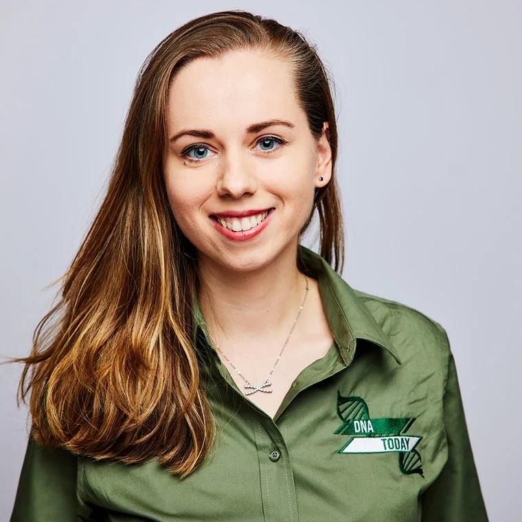 Person smiling with long hair, wearing a green shirt with "DNA Today" logo, against a plain background.