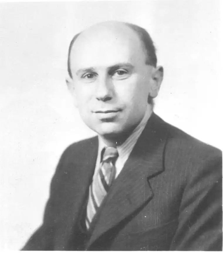 Person in a suit and tie, with short hair, facing forward in a black and white photograph.