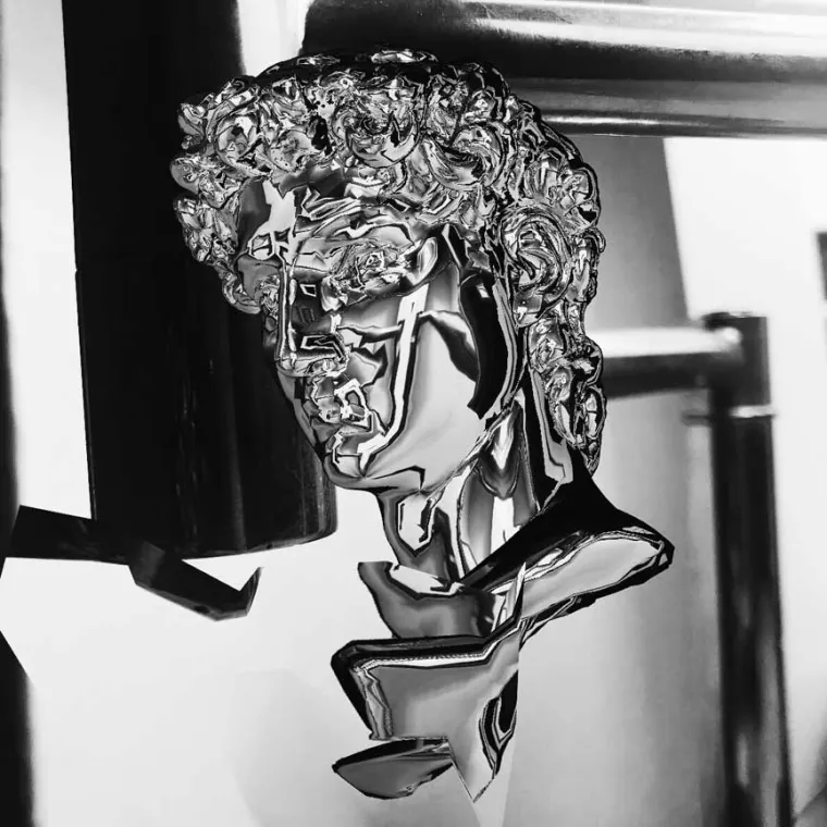 Abstract sculpture of a glossy metallic head resembling classical art, with exaggerated features and reflective surfaces.