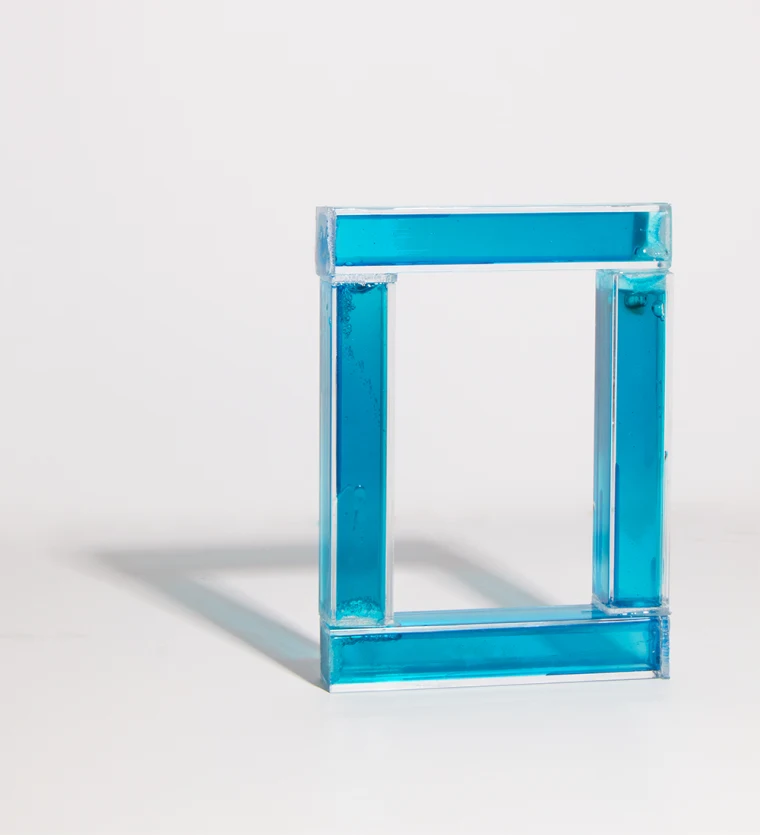 Transparent rectangular frame filled with blue liquid, casting a shadow on a white background.