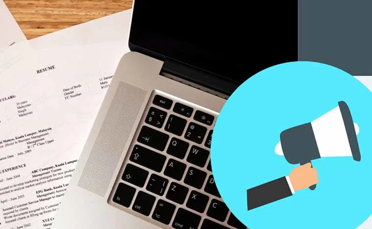 Laptop keyboard next to resumes and an illustration of a hand holding a megaphone against a blue circle.