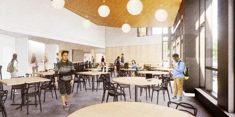 People in a spacious dining area with round tables and large windows. Some are seated, while others stand or walk around with backpacks.