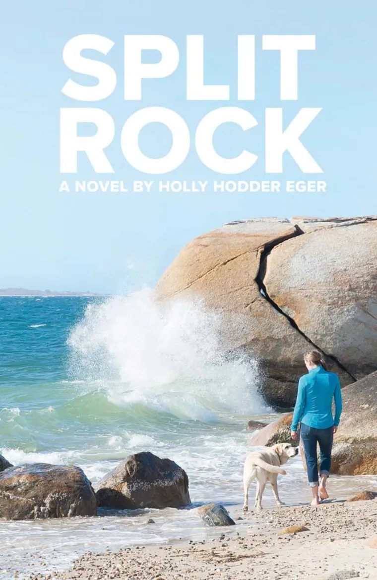 Person in blue shirt walks with dog on rocky beach near crashing waves; text reads "Split Rock: A Novel by Holly Hodder Eger."