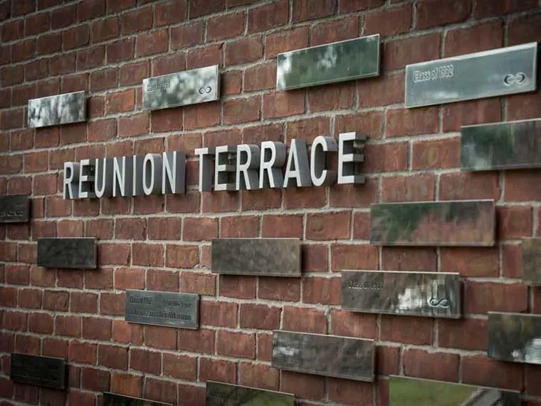 Brick wall with "Reunion Terrace" in large letters, surrounded by scattered metal plaques displaying various inscriptions.
