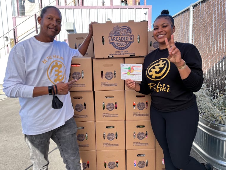 Volunteers stand in front of boxes of produce for donation