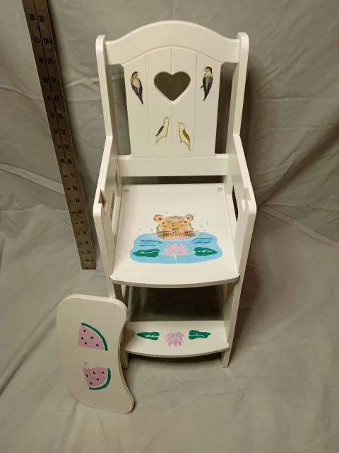 White wooden chair with heart-shaped cutout, bird and animal illustrations, and watermelon slice on detached armrest.