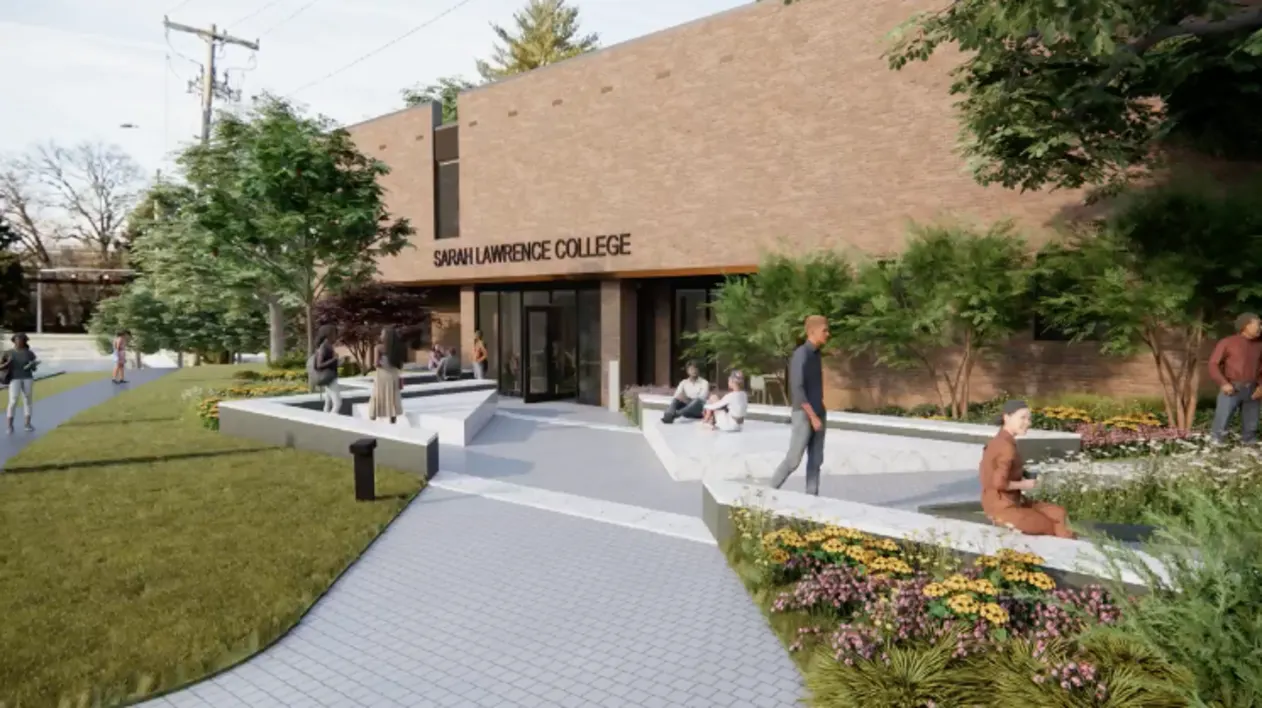 Brick building with "Sarah Lawrence College" above entrance. People are sitting and walking on a landscaped path with flowers and trees.