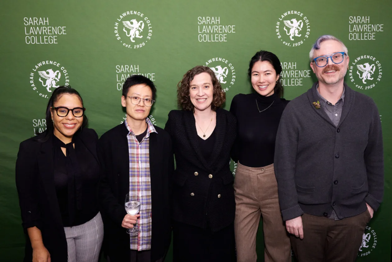 Five people smiling in front of a green Sarah Lawrence College backdrop.
