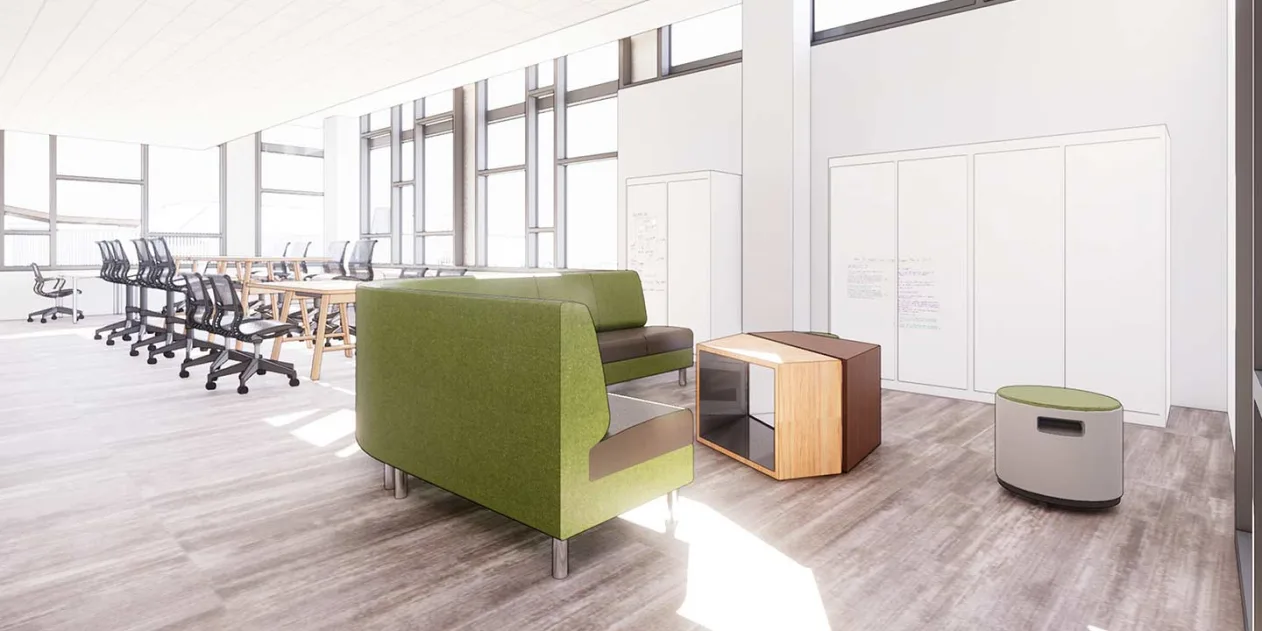 Open office space with green sofas, wooden tables, black chairs, cabinets, and soft natural light streaming through large windows.