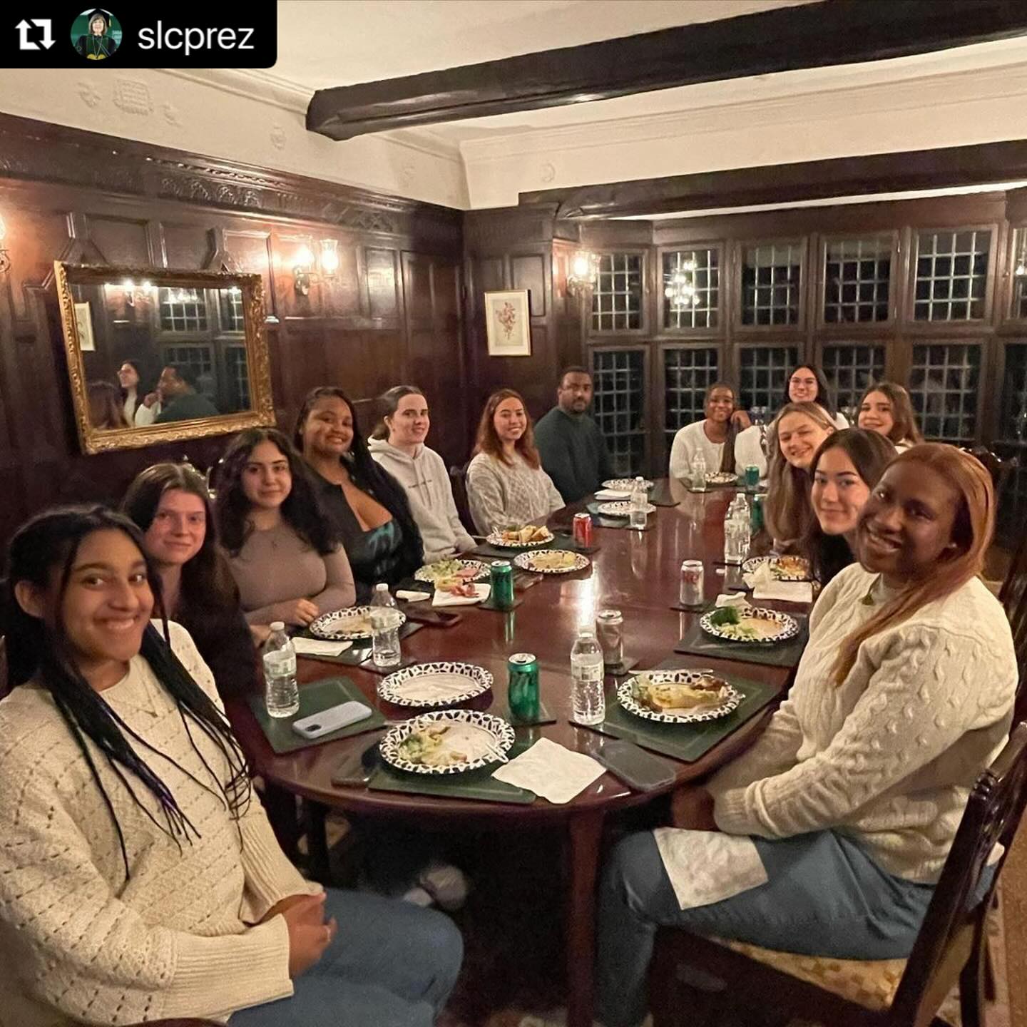 Group of people gathered around a long rectangular dining room table.