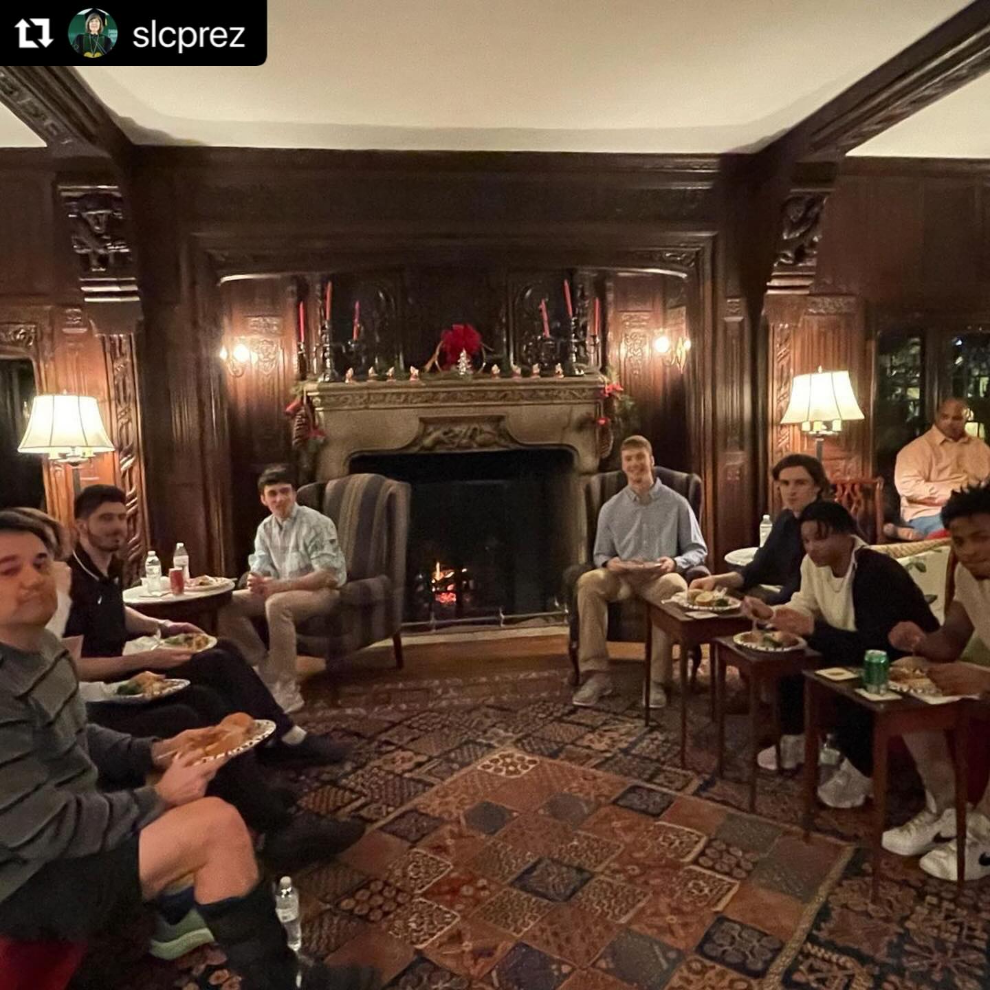 Group of people sitting in a living room with plates of food.