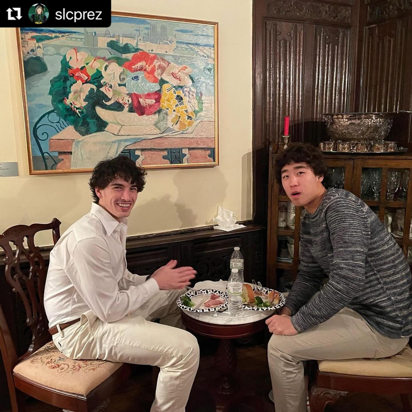 Two people sitting at a small round table with plates of food.