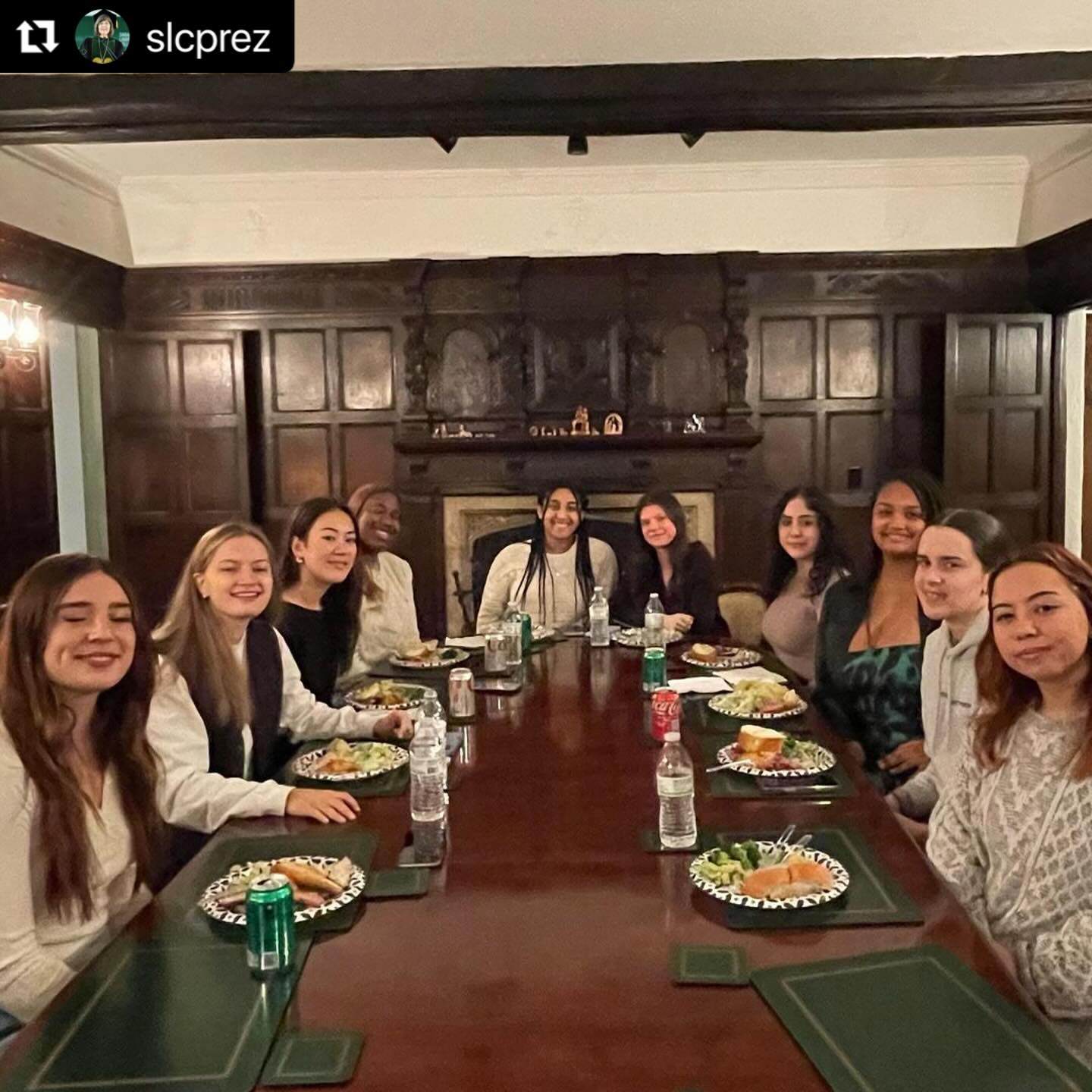 Group of people gathered around a long rectangular dining room table.