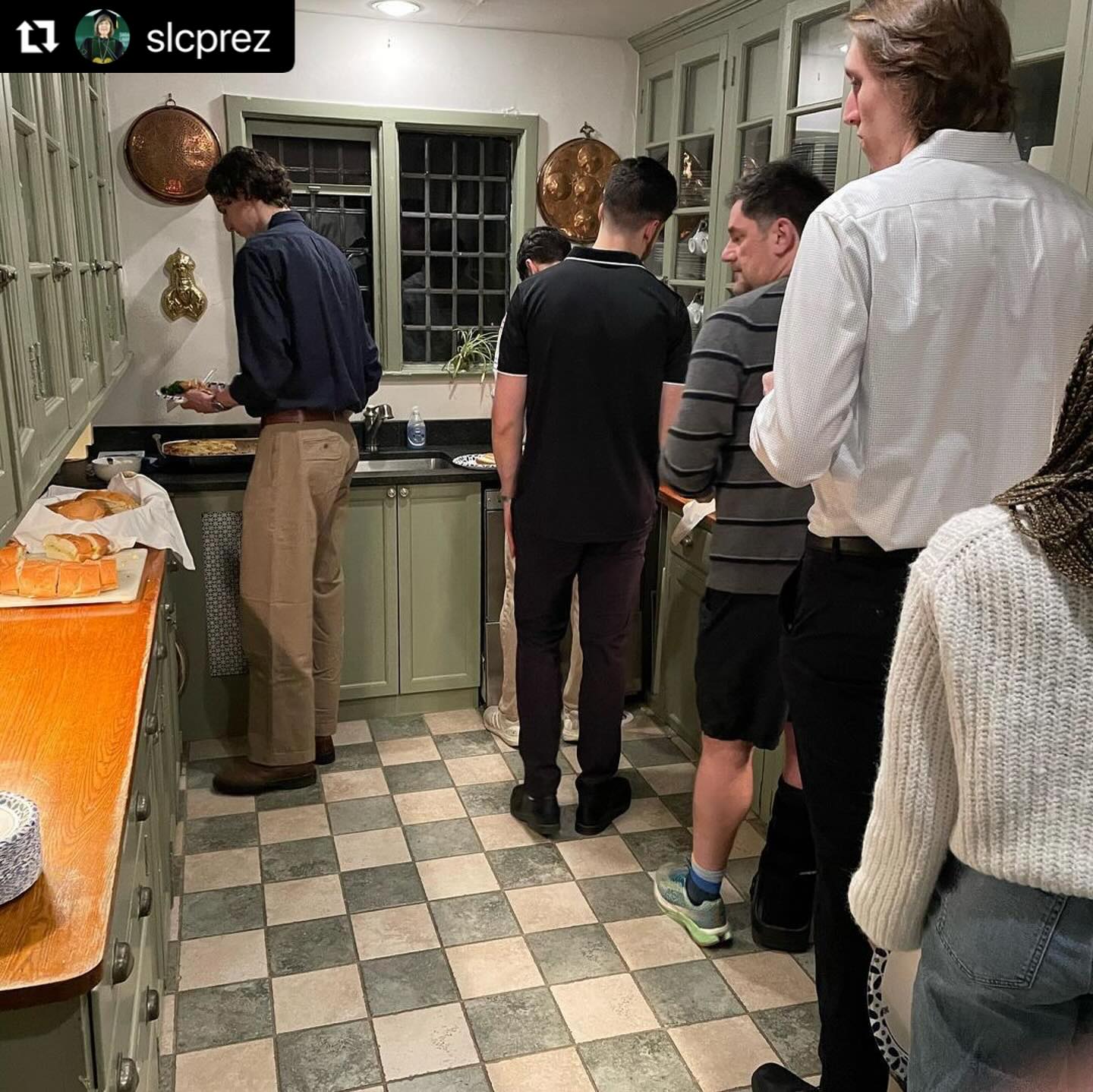 People in a kitchen lining up for food.