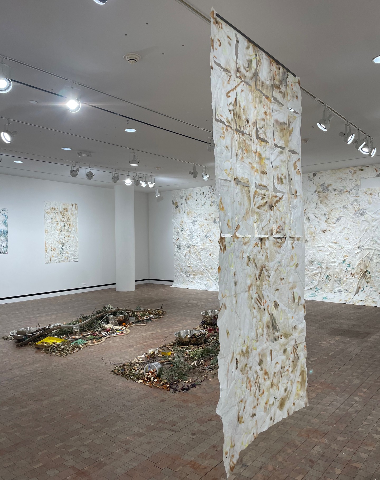 Abstract art exhibition with hanging fabric and floor installations.