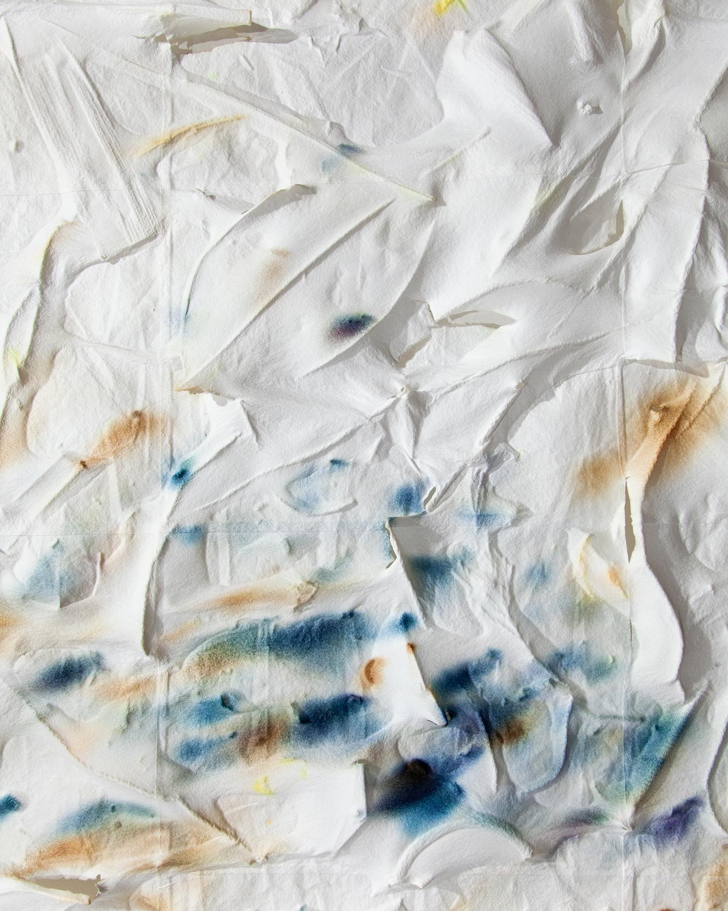A crumpled piece of paper with blue and yellow watercolor stains.