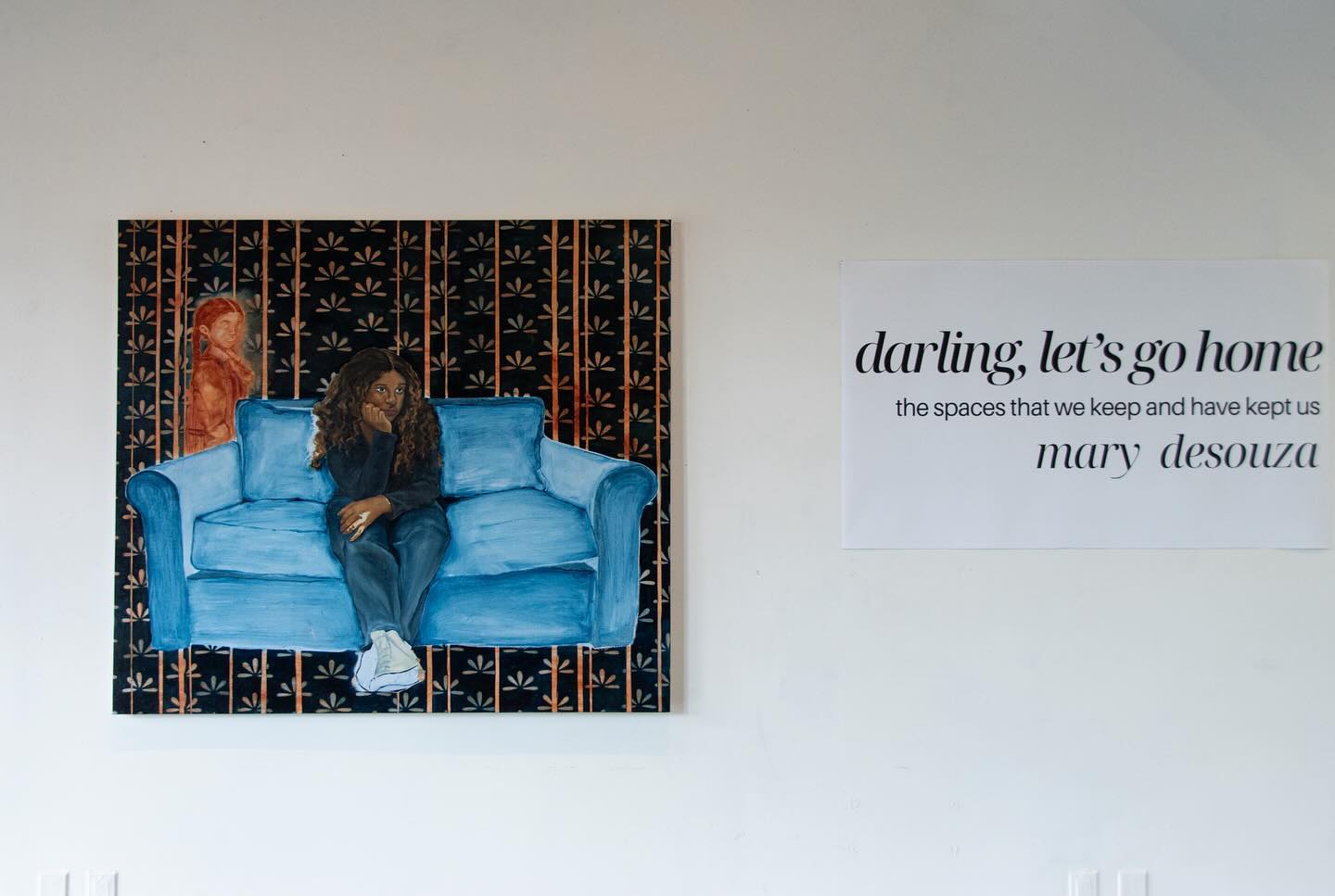 Painting of a person on a blue sofa and a text poster on a wall.