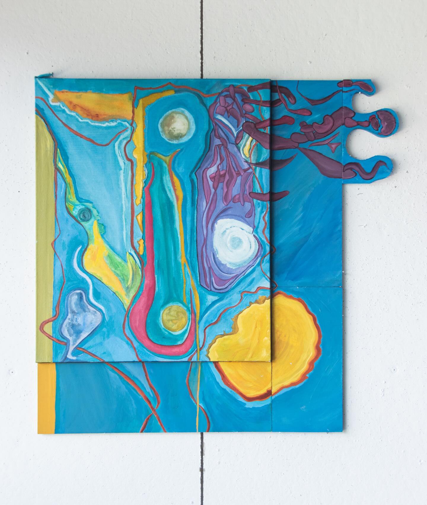 Abstract painting with vibrant colors mounted on a white wall.