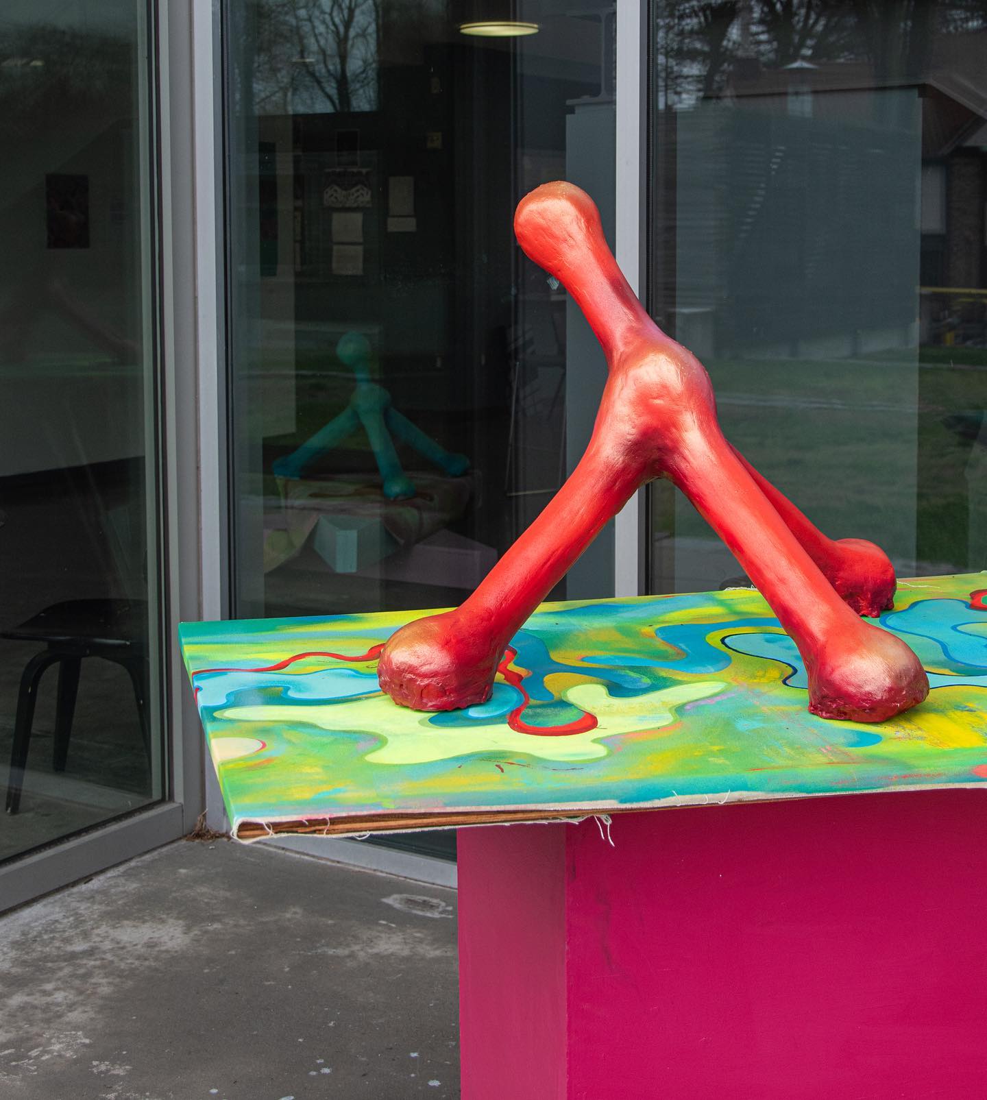 Colorful abstract sculpture on a vibrantly painted surface, near a glass door.