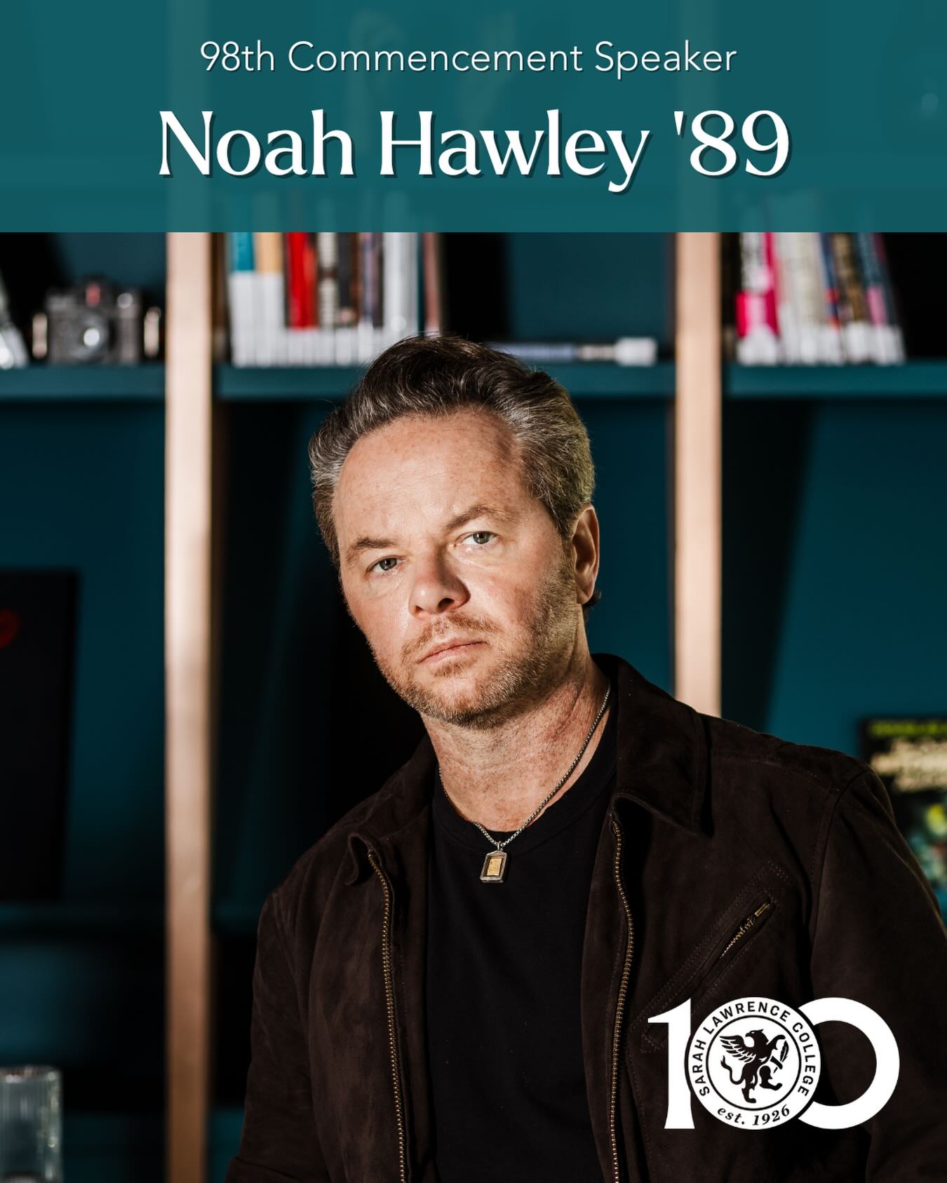 Person with short hair and a necklace, wearing a dark jacket, stands in front of bookshelves. Text: "98th Commencement Speaker, Noah Hawley '89."