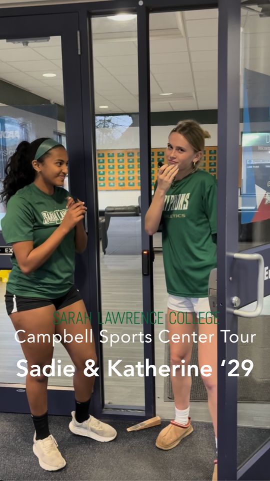 Two people in green sports shirts stand at a glass door entrance of Campbell Sports Center at Sarah Lawrence College. Text reads "Sadie &amp; Katherine '29".