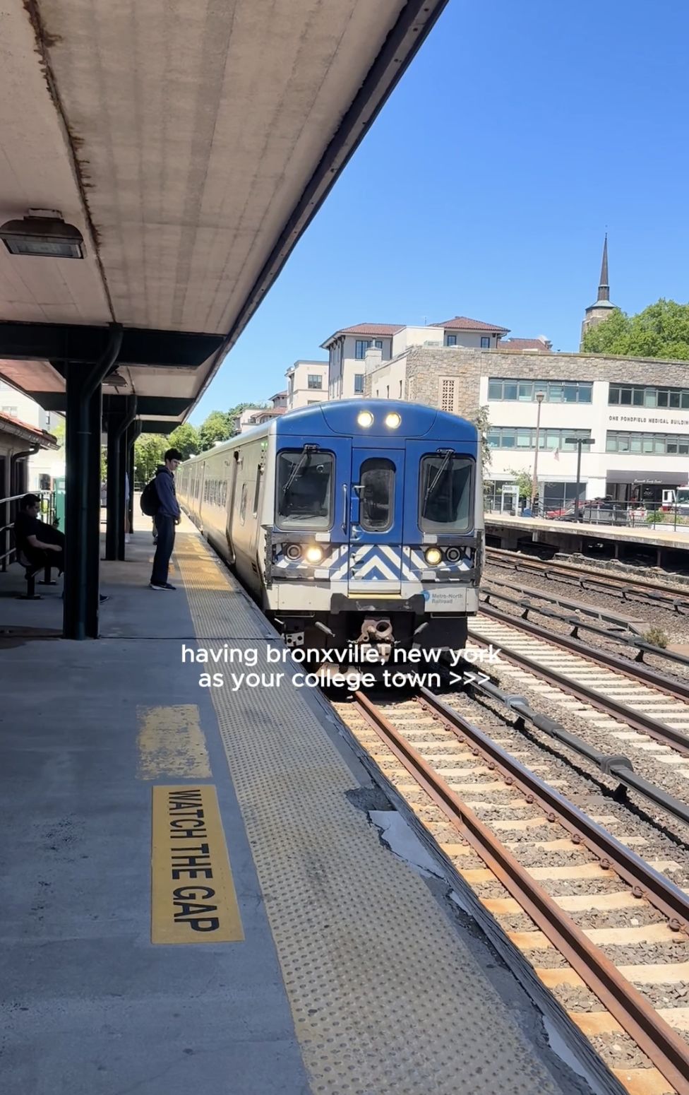 Train arriving at a station in Bronxville, New York. Platform sign reads "WATCH THE GAP." Text overlay mentions the area as a college town.