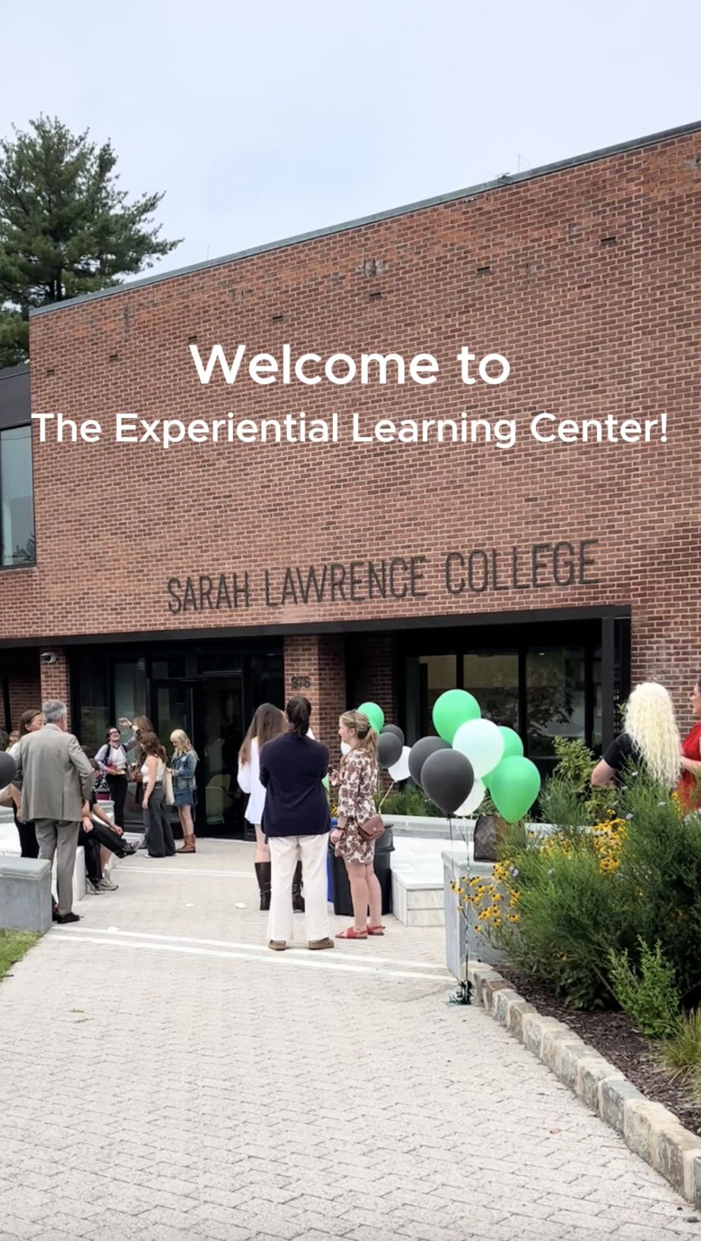 People gathered outside Sarah Lawrence College's Experiential Learning Center. Green and black balloons are displayed.