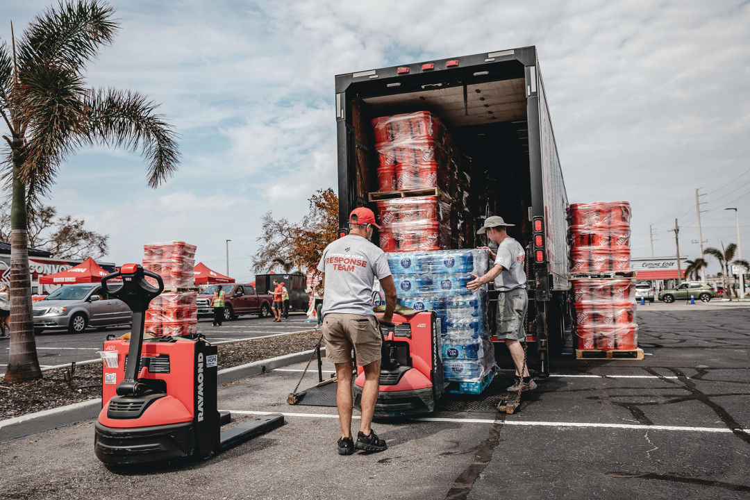 Response teams unload bottled water and buckets to distribute to residents affected by the hurricanes at CoastLife Church in Venice.