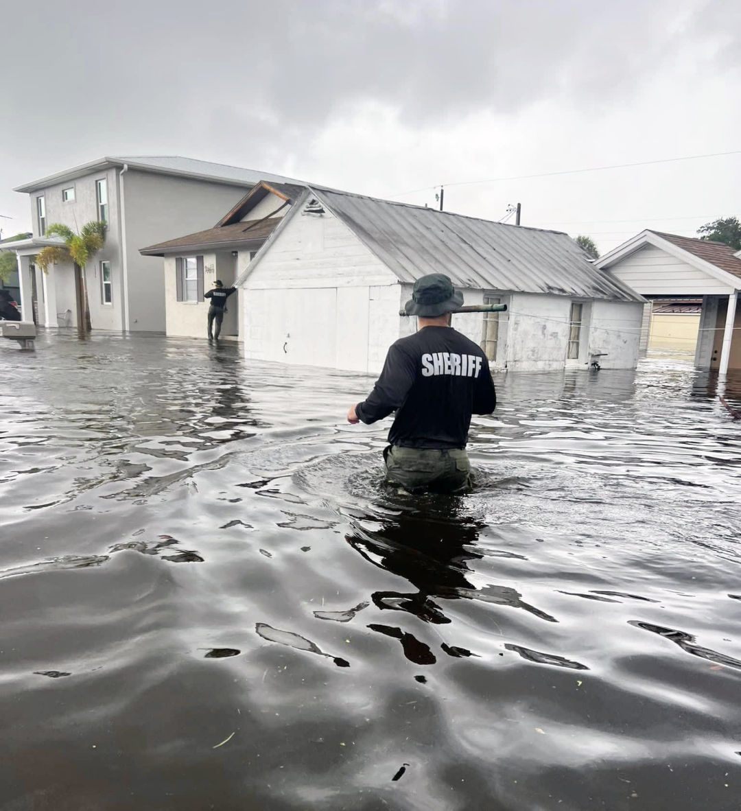 A law enforcement officer wades through flooding brought by Hurricane Debby's record rainfall.