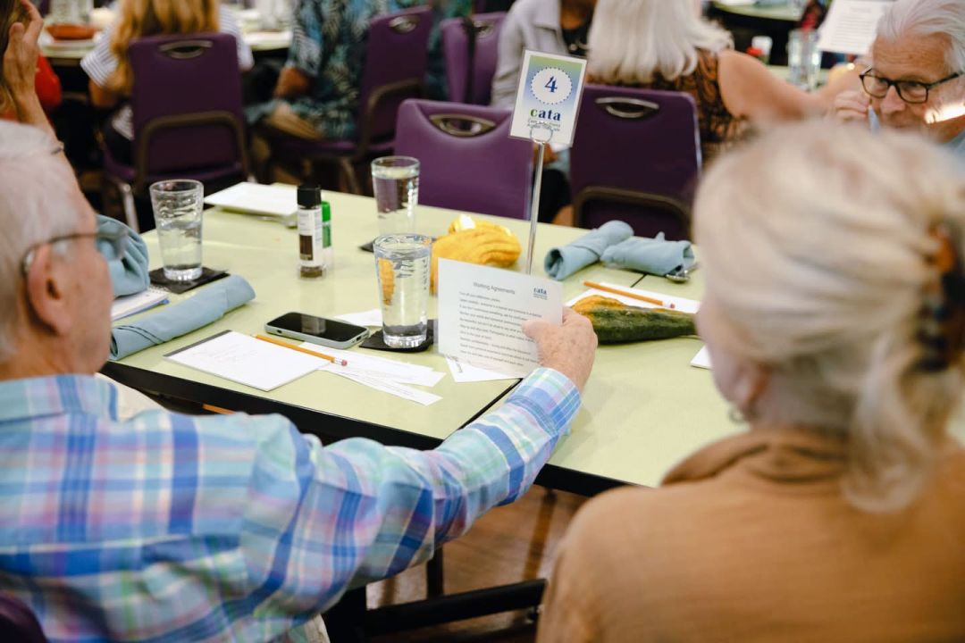 Each table, filled with six to eight guests, discusses the topic through guided questions that require nuanced responses rather than simple black-and-white answers.