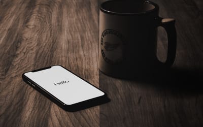 Phone screen on a table beside a coffee cup.