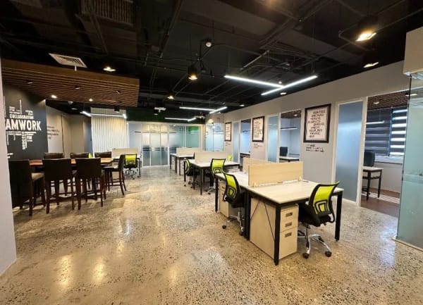Open-plan flexible workspace in Alabang CBD with hot desks, high tables, and private cabins along the wall