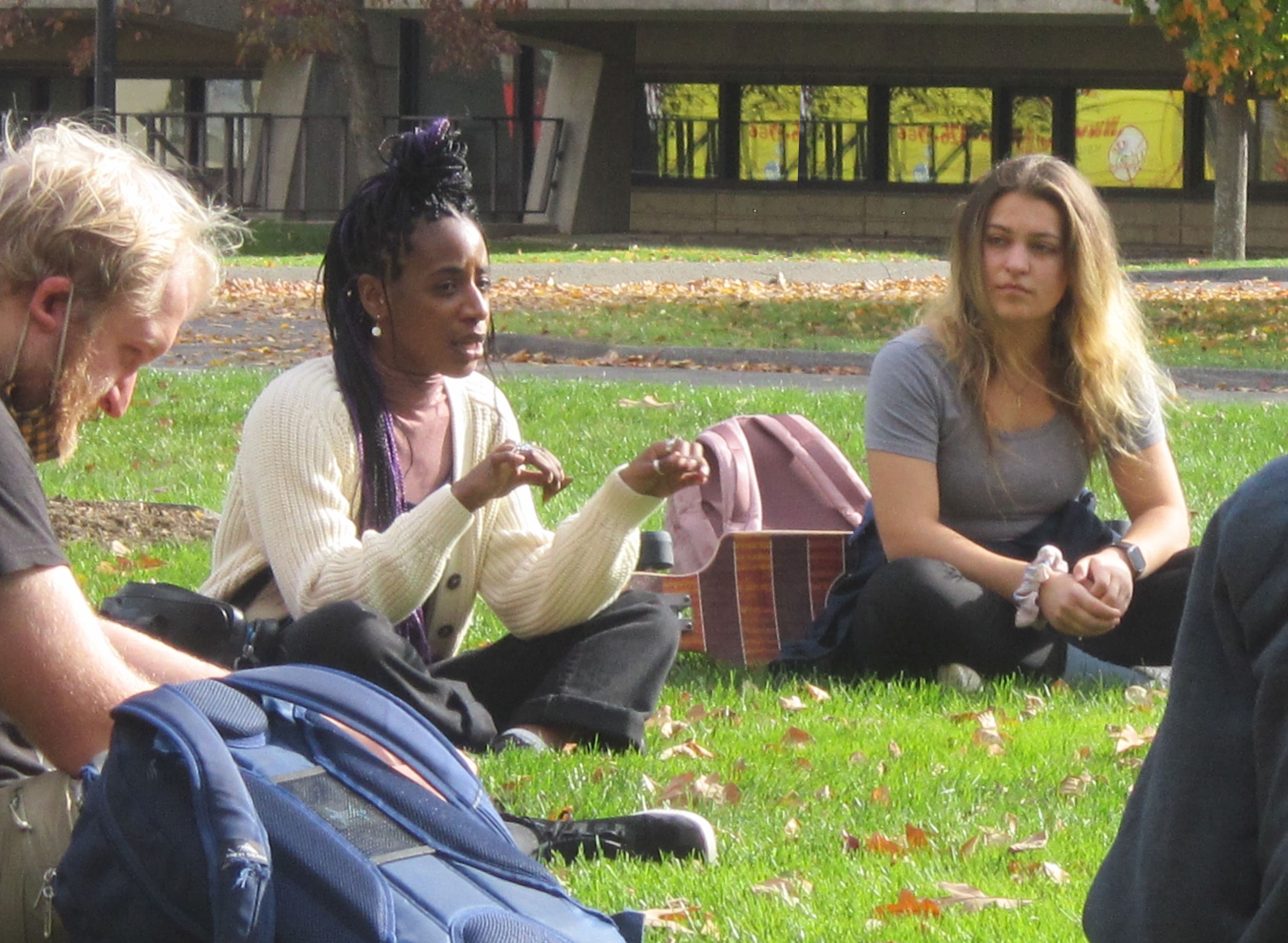 English graduate students sitting outside on the grass in a circle.