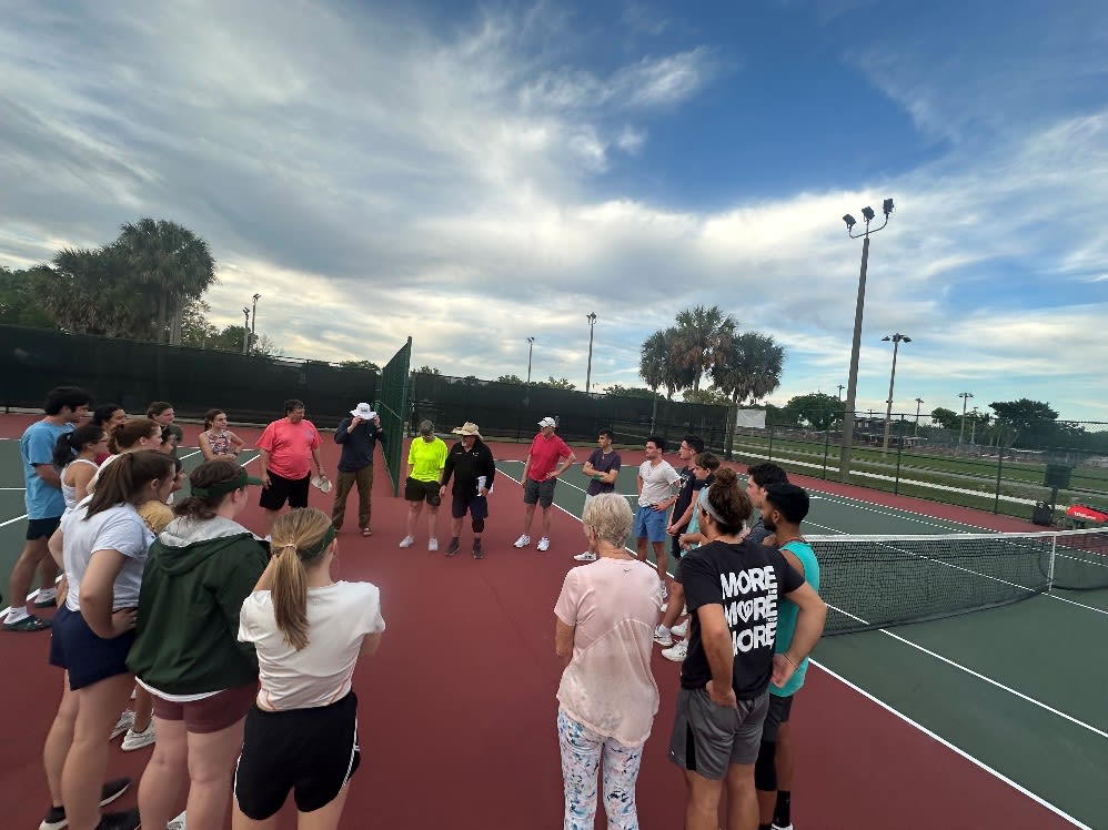 A group of people on a tennis court

Description automatically generated