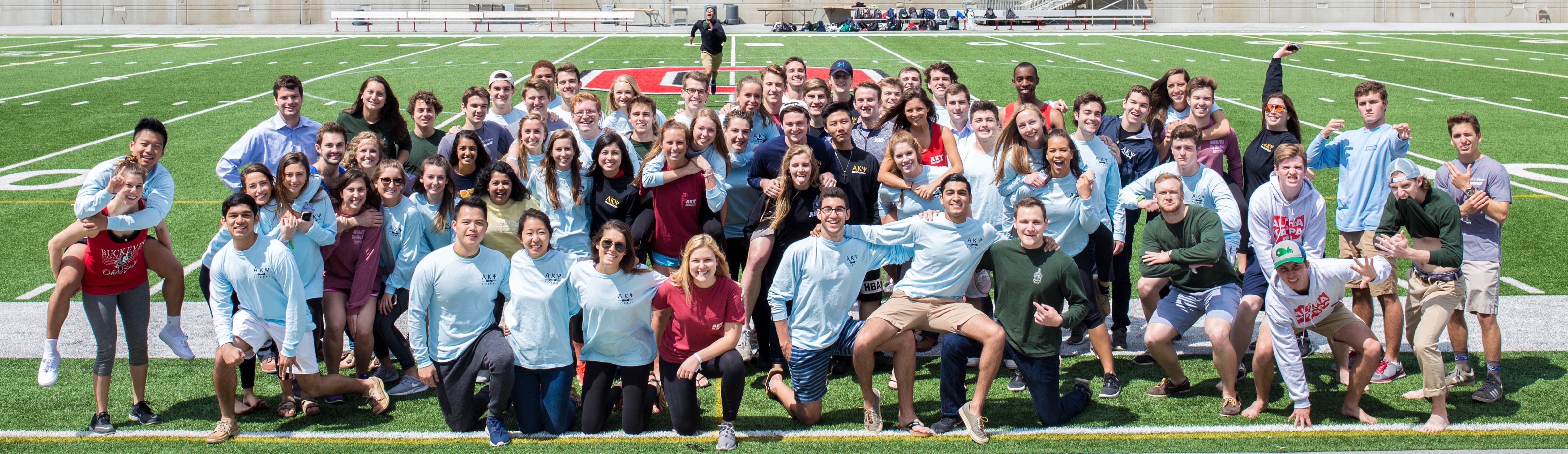 Members of Alpha Kappa Psi on the sideline of The Shoe's football field