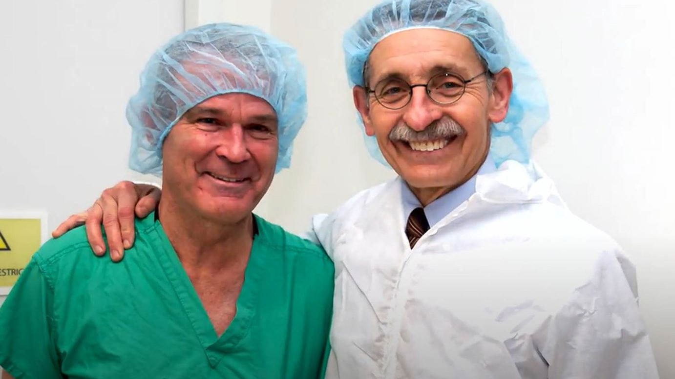 Dr. Farrar (left), and David Schuller, MD (right) standing in an exam room in medical garb