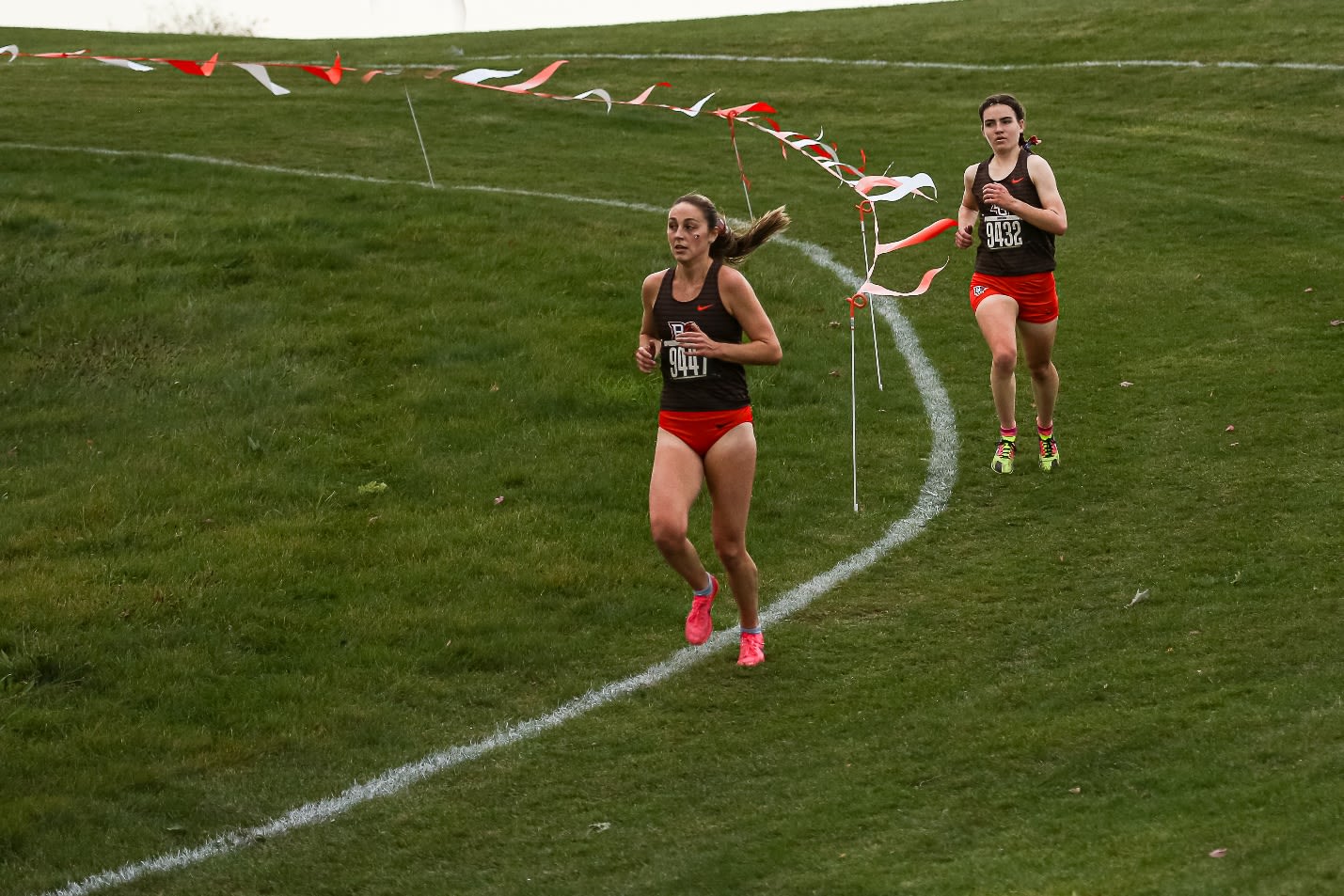 A group of women running on a grass field

Description automatically generated