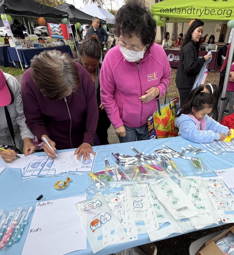 Attendees at community events fill out their names and pick up free oral hygiene packs.
