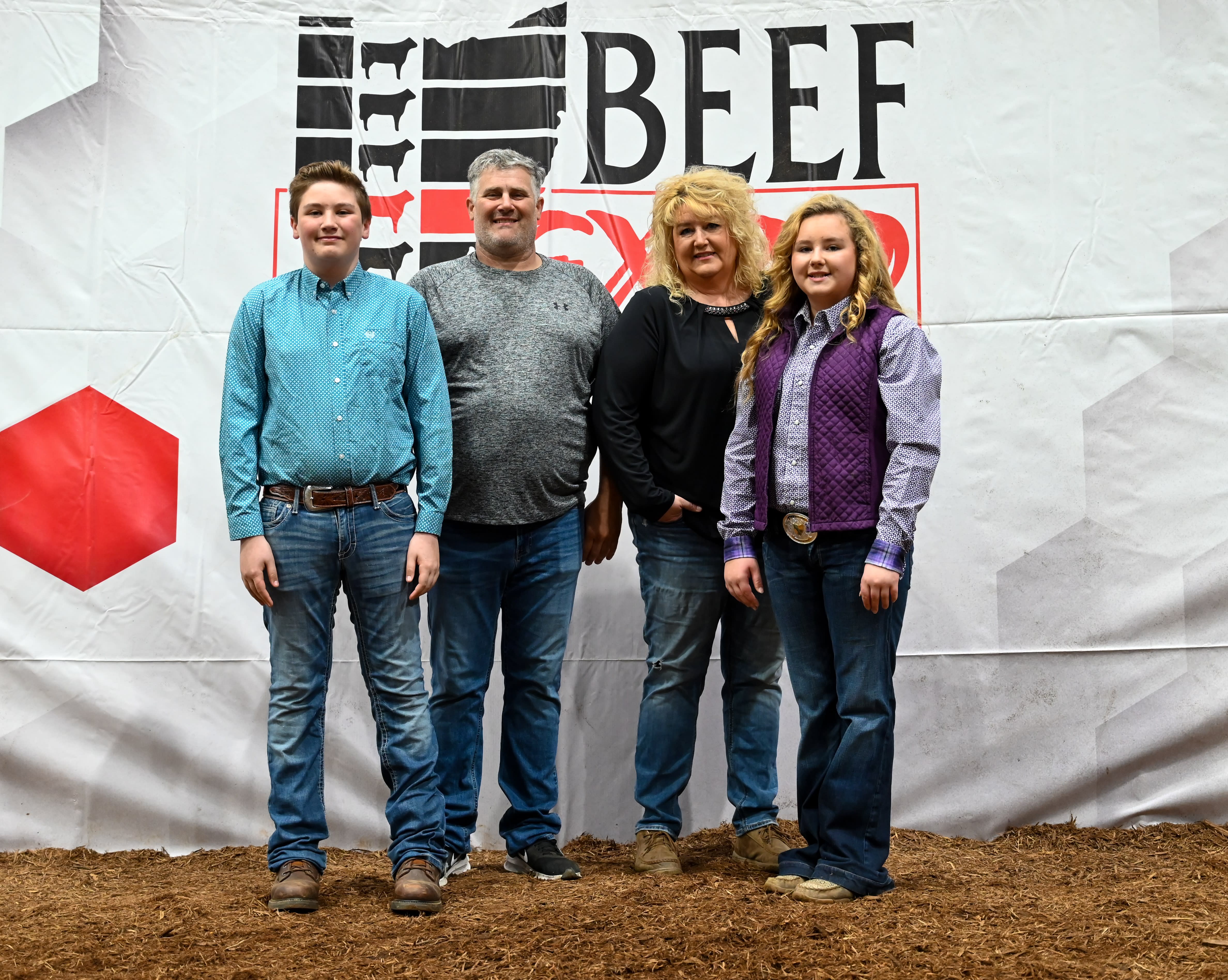 Four members of a family stands with the Beef Expo logo behind them 