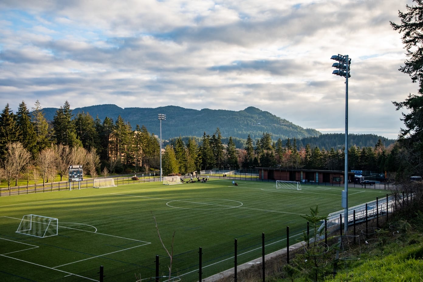 A football field with trees and mountains in the background

Description automatically generated with medium confidence