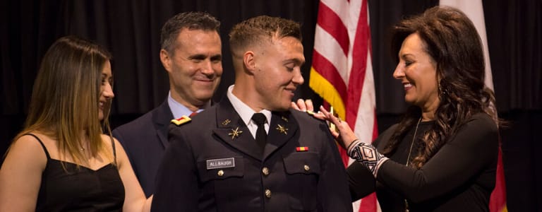 cadet being pinned with by mother with father and sister standing around him