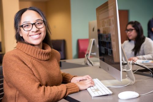 A person sitting at a desk using a computer
Description automatically generated