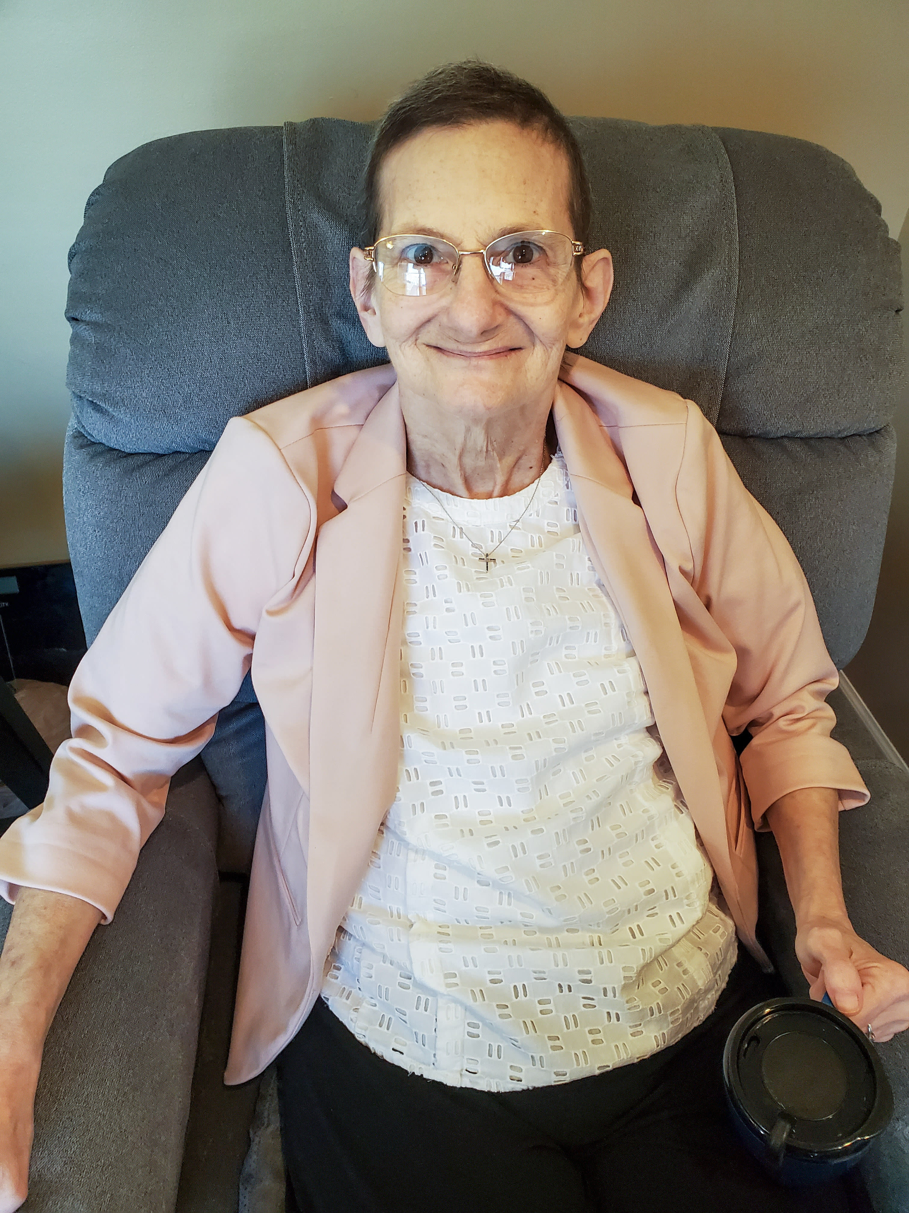 Laurie sitting on a grey armchair, smiling up to the camera 