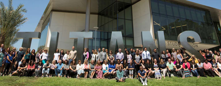 3 rows of 25 students in front of a metal letters spelling out TITAN