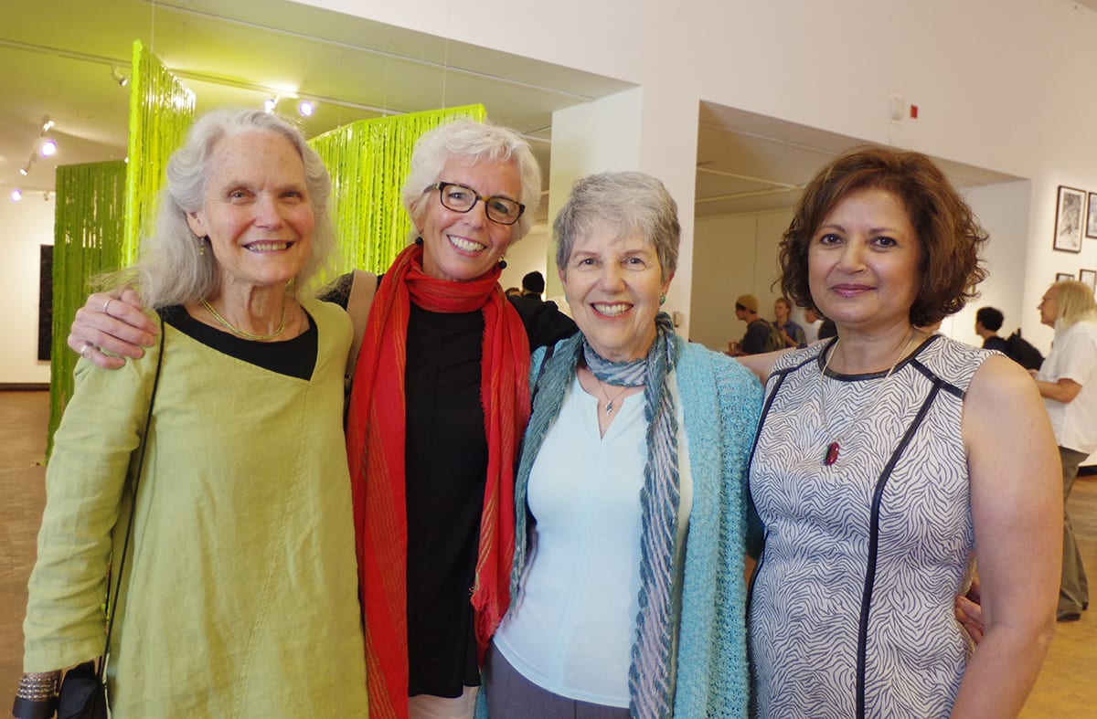 four people stand a row, smiling at the camera. One of them wears a bright red scarf - that's Susan.