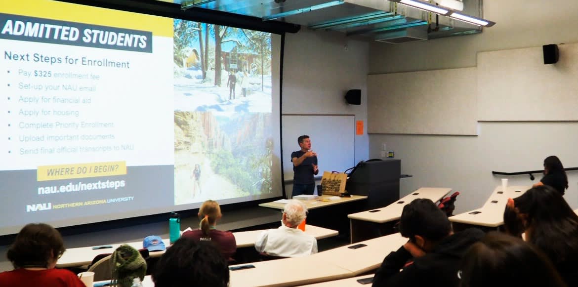 A person giving a power point slide on the Media Workshop to potential participants.